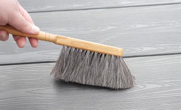 Tischhandfeger mit grauem Ziegenhaar-Besatz. Dieser fegt graues Laminat.
